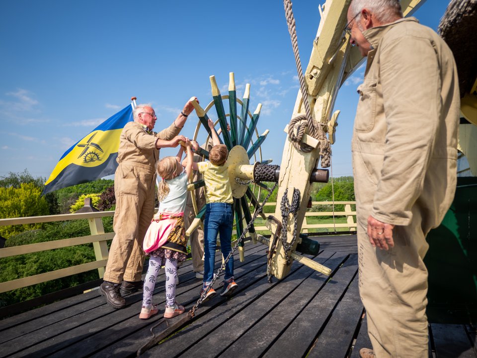 Kinderen en molenaars bij het kruirad van Molen Nooit Gedacht in Warnsveld