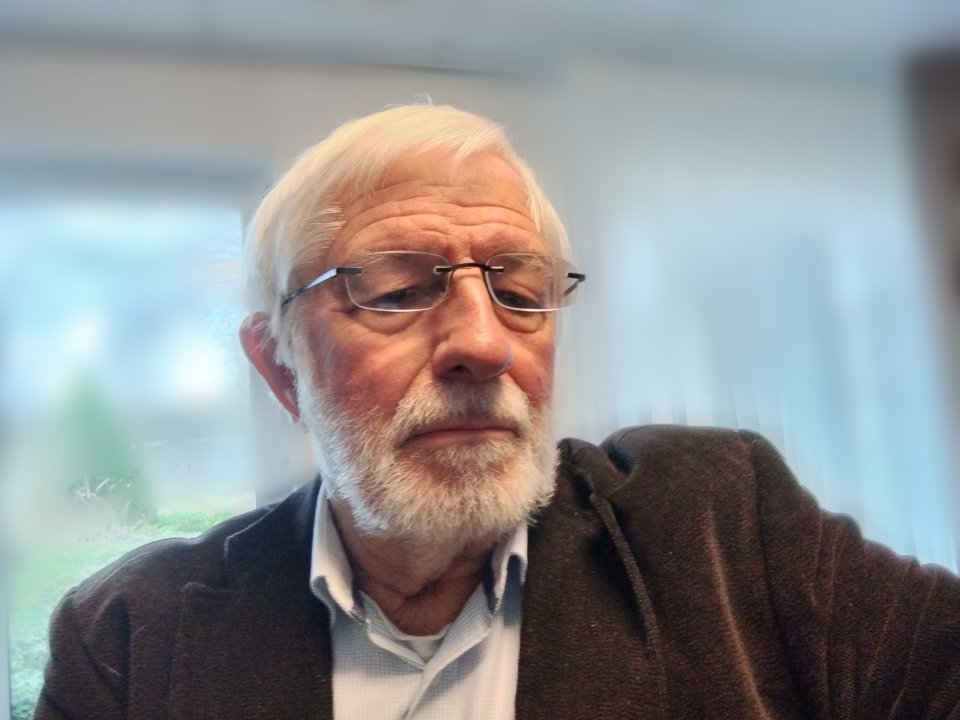 Portretfoto van Jos: hij heeft een baard en een bril op en een net jasje aan..